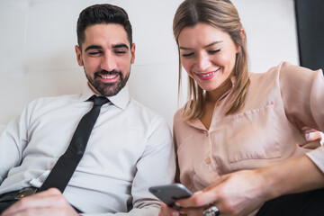 Business people lying on bed and using mobile phone.