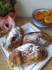 Pies with powdered sugar on white square plate a bowl of apricots jam and a cactus flower