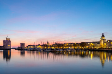Fototapeta na wymiar Panoramic view of the old harbor of La Rochelle at sunset with its famous old towers. beautiful pastel color sky