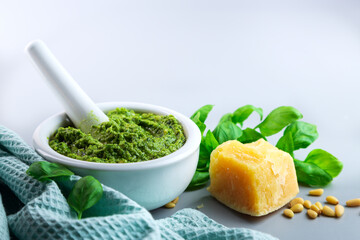 Homemade basil pesto on a gray table. Basil leaves. Horizontal. Selective focus. Copy space.