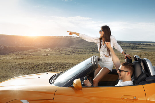 Cheerful young couple going on a long drive in a convertible car. Freedom, travel and love concept.