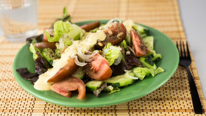 vegetable salad of greens, tomatoes and cucumbers on a green plate