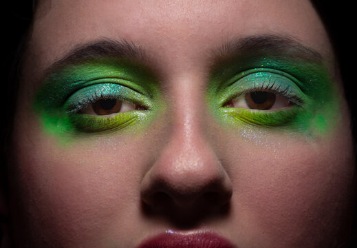 ojos con maquillaje verde y turquesa mirando a c&aacute;mara en primer plano 