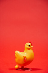 Concepto gallina amarilla de plástico protegiendo huevo en fondo rojo