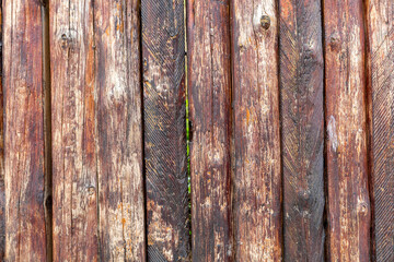 Old wooden fence of dark brown boards. Abstract background, natural texture.