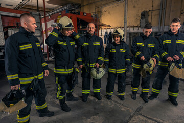 Naklejka premium Portrait of firefighters standing by a fire engine.