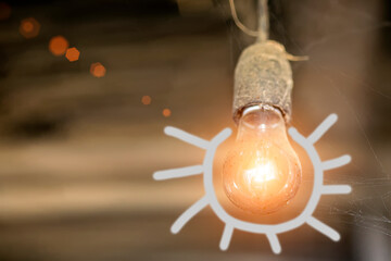 Old incandescent lamp with painted rays in the dust and cobweb on a brown background.