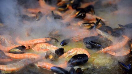 Riesige Pfanne mit im Dampf garenden Muscheln und Garnelen © thauwald-pictures