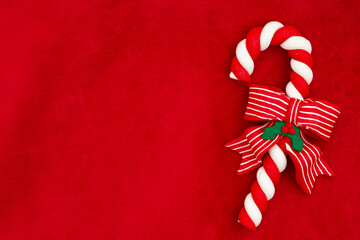 Christmas background with red plush material and a candy cane with a bow