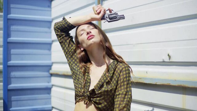beautiful woman with a gun aiming at the camera. pointed a gun at the camera, on the street