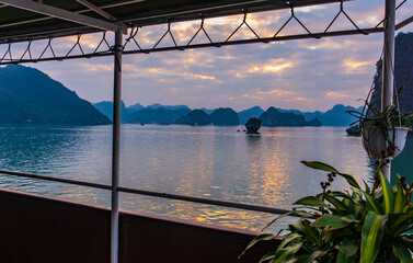 view from a tourist boat deck of the evening skies on Halong Bay among the limestone karsts
