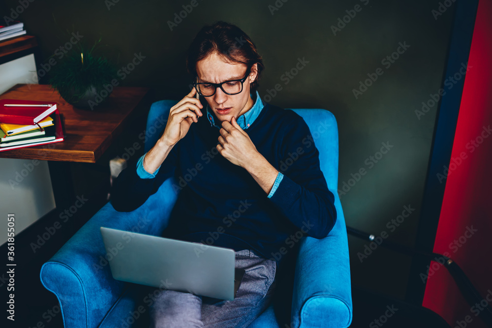 Aufkleber serious male freelancer having telephone conversation and checking mail via laptop computer, man cal