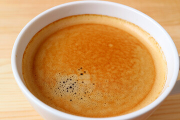 closeup the texture of hot black coffee surface in a white cup
