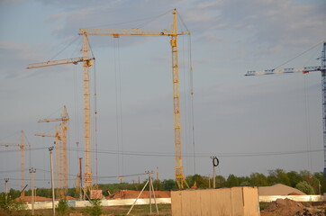 Inside place for many tall buildings under construction and cranes under a blue sky working on place with tall homes