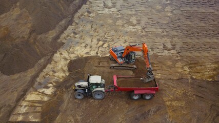 Baustelle: Tiefbau Erdbau Bauarbeiten: Bagger verlädt Erde, Sand auf einen Muldenkipper, Luftbild