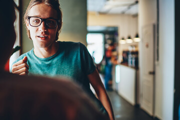 Cropped image of handsome male in eyewear looking at his female colleague while asking...