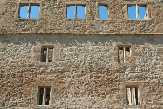 Facade of a brown castle wall, many beautiful windows to see, blue daylight. Germany.