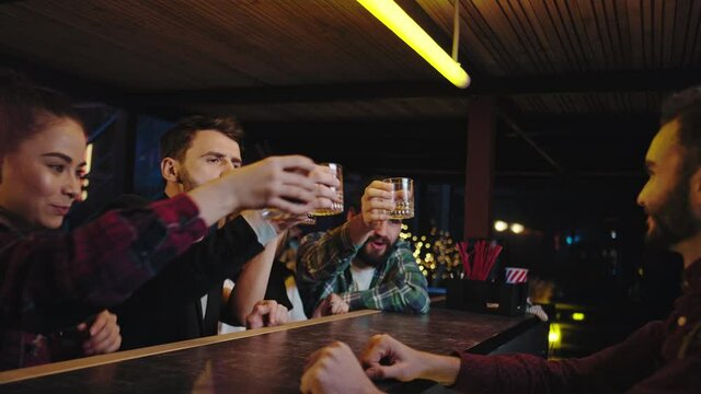 Pretty ladies and good looking guys enjoying the evening time in a modern bar they drinking some cocktails feeling relaxed then happy going home bartender start to cleaning the work place