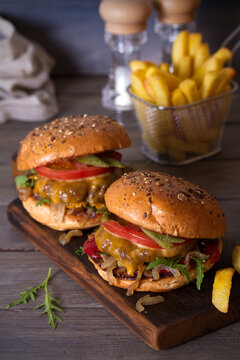 Beef burgers and french fries on wooden table. Vertical image