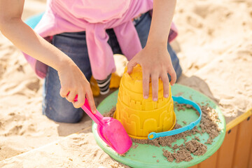 Small cute girl shares a sand castle in a sandbox