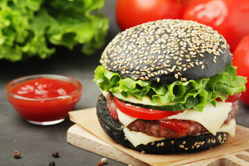 A black burger with vegetables and beef meat