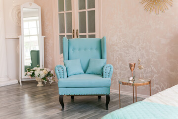 Real photo of a feminine bedroom interior with a comfy armchair, bed
