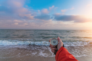 First-person view of a female hand with a compass on a background of a beautiful sea landscape. The concept of navigating the search for your own path and orientation to the cardinal points © Валентина Баранова