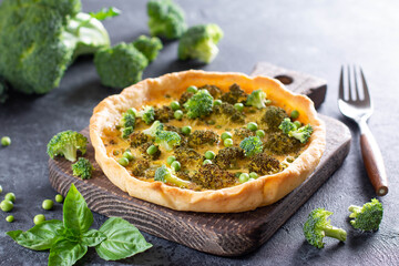 Vegetable pie ( quiche) with broccoli and soft cheese on a dark concrete background. Traditional French food.