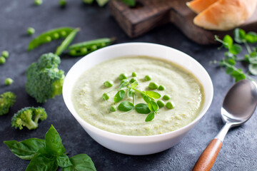 Summer cream soup with green fresh pea, shoots close-up on a concrete background