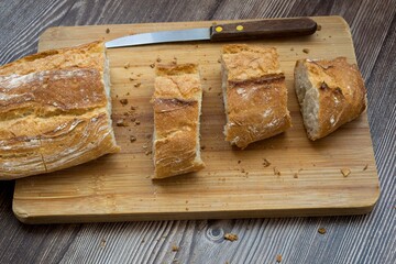 High angle shot of a freshly-baked breast on a wooden cutting board with a knife