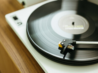 Modern record player playing a vinyl on a wood table.