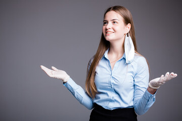 Girl business lady stands with arms apart and smiles at the end of quarantine on a gray background