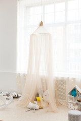 children's room in pastel colors with fabric tent and toys