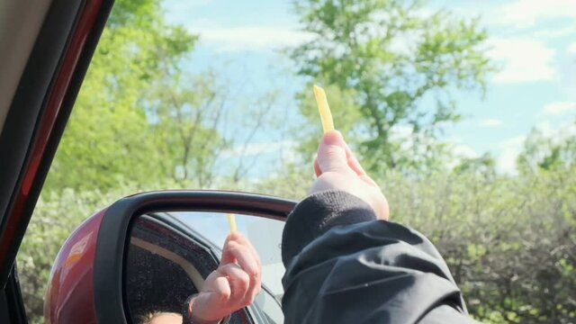 woman feeds bird with french fries giving fast food from car window.