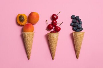 Overhead view of waffle cones with summer fruits (apricots, blueberry, cherry)