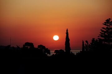 Obraz premium Silhouette landscape with sunrise over trees and sea