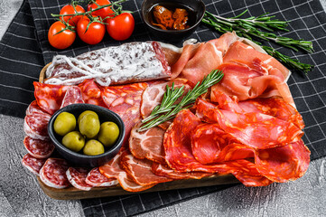Cured meat platter of traditional Spanish tapas. Chorizo, jamon serrano, lomo and fuet. Gray background. Top view