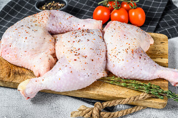 Fresh raw chicken thighs, legs on a cutting Board with spices, cooking. Gray background. Top view. Copy space