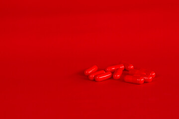 Pills of red color on a neutral red background. Legal drugs from the pharmaceutical industry. Medications for human use