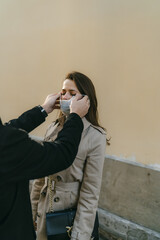 Guy helps to put on a girl's medical mask during coronavirus epidemic