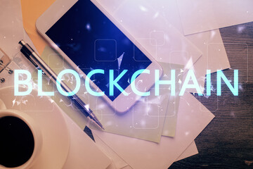 Double exposure of blockchain theme hologram over table with phone. Top view. Crypto technology...