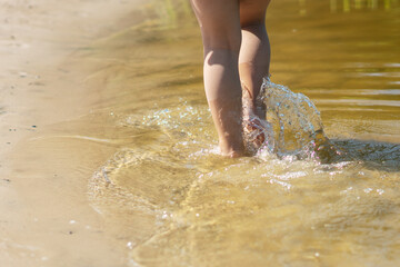 A child runs along the river bank splashing water with his feet