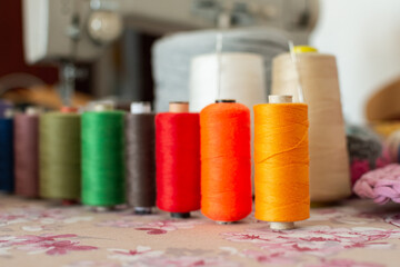 Colorful sewing threads with sewing machine in the background at home
