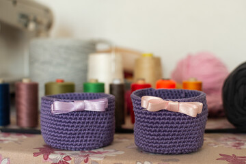 Fototapeta na wymiar Purple knitting basket with ribbon and sewing threads in the background