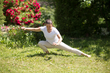 Fototapeta premium Woman practice Tai Chi Chuan in a park. Chinese management skill Qi's energy. solo outdoor activities. Social Distancing 