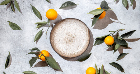 Whole oranges witl orange tree leaves on white background around empty plate. top view, flat lay, summer and healthy concept. Mockup