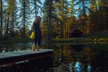 Fototapeta na wymiar Chica joven en un entorno de naturaleza, bosque y lago, durante la puesta de sol.