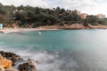 sea water reaching the rocks in front of a beach in front of some houses