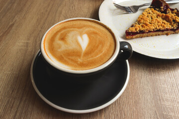 Cup of cappuccino in a coffee shop with grated berry pie. Breakfast concept