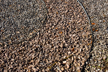 Metal edging separating different colors of gravel in a park